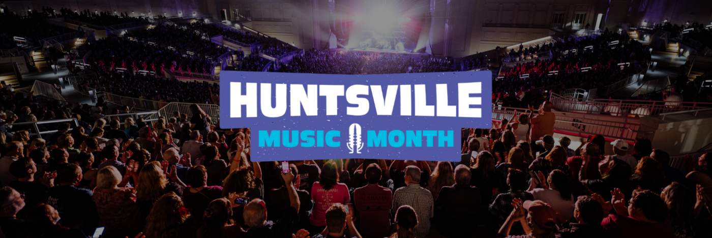 Logo in the center with the words Huntsville Music Month against a background image of The Orion Amphitheater during a concert. Shows hundreds of people looking in the direction of a brightly lit stage.