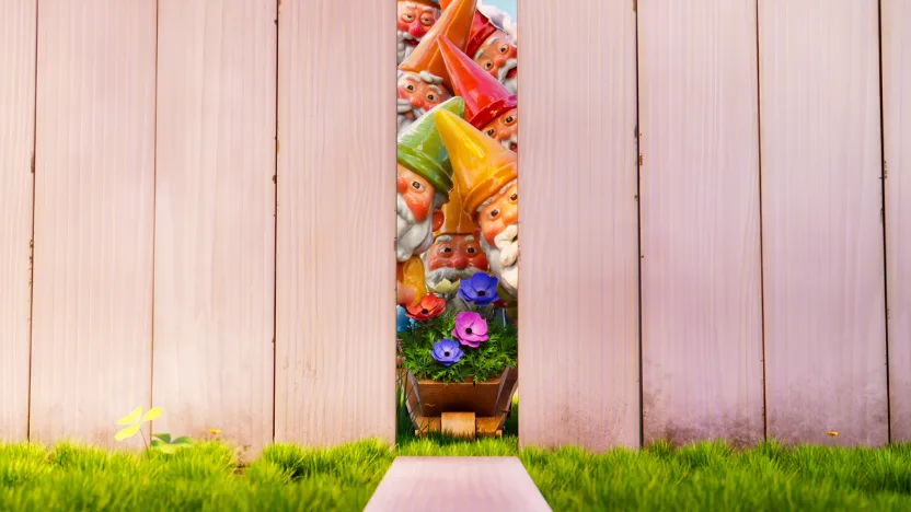 A row of colorful garden gnomes with bright hats and white beards are tightly packed behind a wooden fence, peeking through a narrow vertical gap. In front of them sits a small flower box with blooming purple and pink flowers, surrounded by green grass.