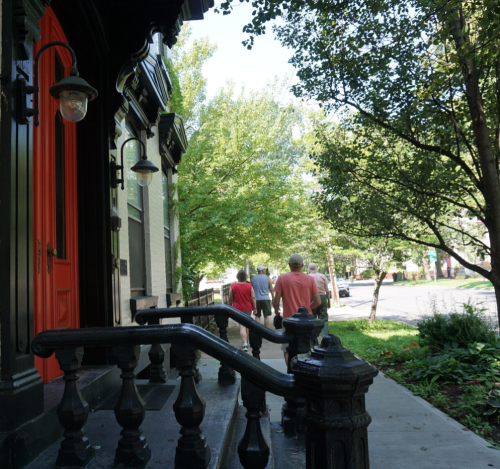 This photo depicts part of the trail that goes through the Stockade on Union Street, with people walking on the sidewalk by historical buildings.