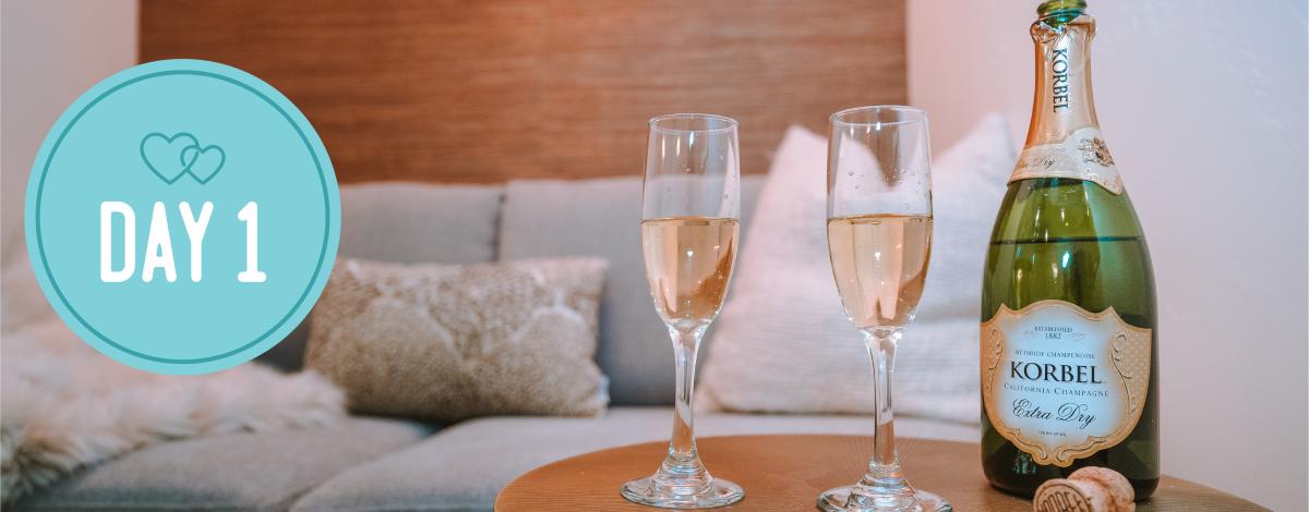 Day 1. Image of two glasses and a bottle of campaign. Couch in background.