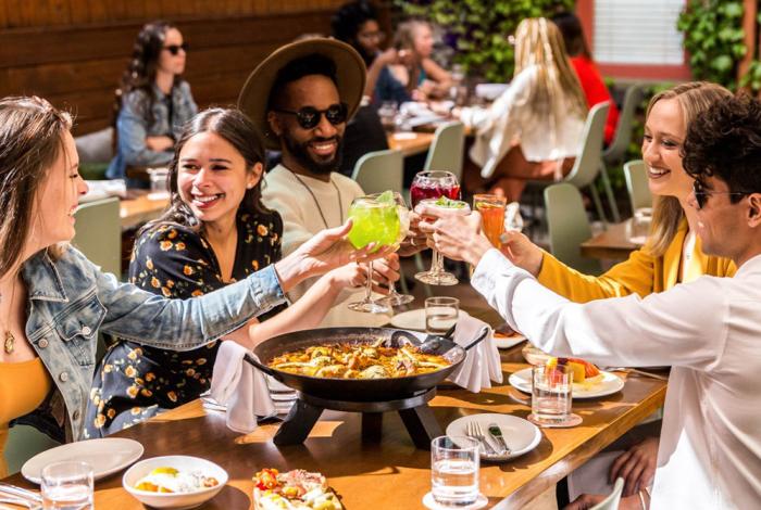 Group of people cheers glasses at outdoor table