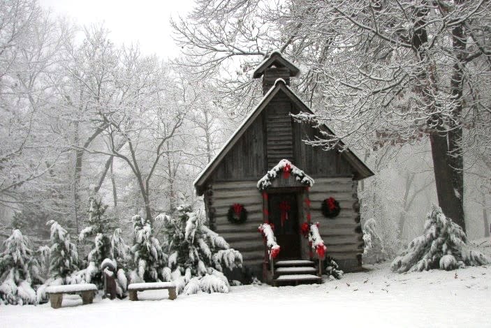 A small wooden building with wreaths hanging on either side of the door is covered in snow at LaGrange College Site Park