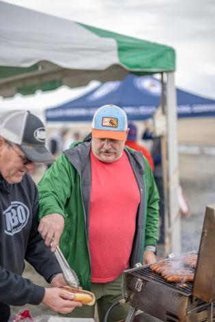 Two men grilling hot dogs on the beach at the Cannon Beach Fat Bike Festival.