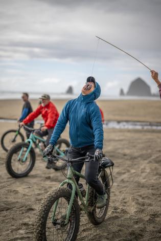 Someone riding their fat tire bike tires to bite a donut that is being dangled in the air by a rope without using their hands.