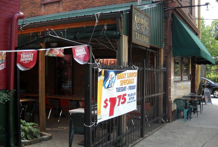 Image is of the side of Mansion Hill Tavern where you can see their sign which say's Mansion Hill Tavern and their back patio.