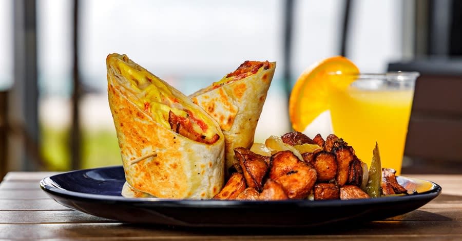 A breakfast burrito with hashbrowns and a mimosa
