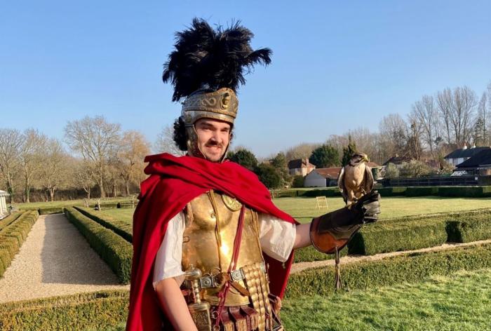 A man dressed as a Roman Gladiator holding a bird of prey
