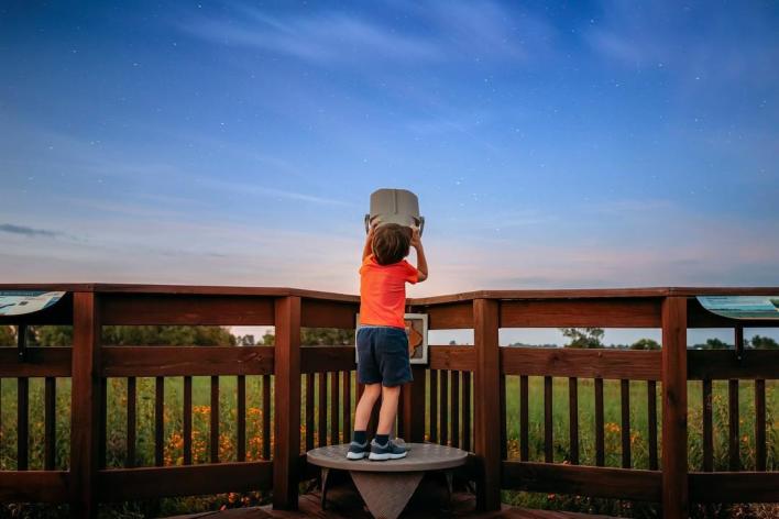 A child looks through binoculars at Chichaqua Bottoms Greenbelt