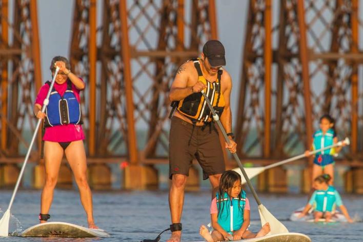 5 people paddle-boarding on a body of water