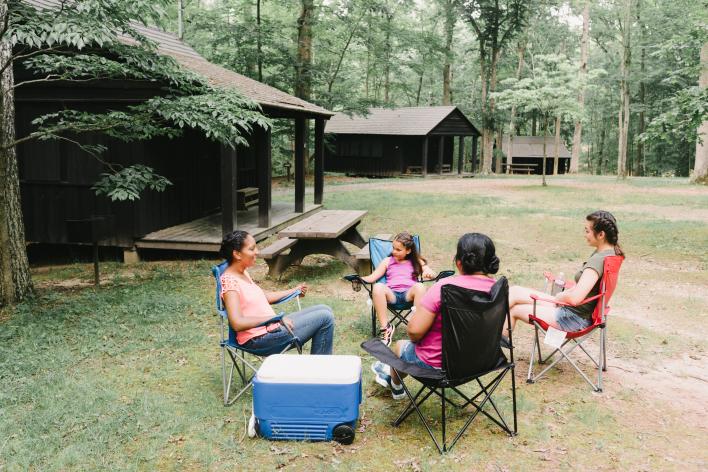 People sitting in folding chairs outside of a cabin