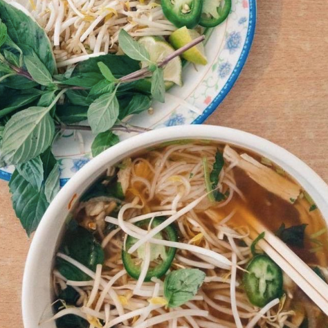 A bowl of Pho from Bida Saigon is topped with bean sprouts, basil, peppers and lime.