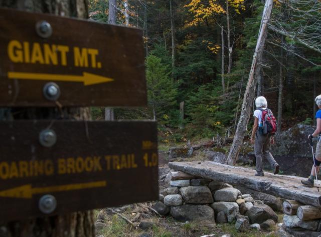Two senior hikers march their way along a wooden bridge on the Trail to Giant Mountain at Giant Washbowl