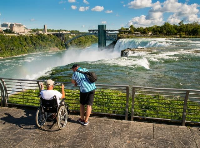 A man in a wheelchair and a companion look out at Niagara Falls