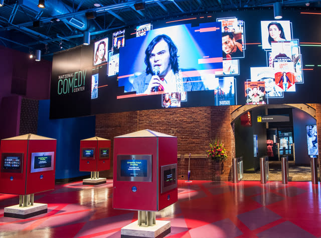 Large digital screens showing various comedians inside the National Comedy Center in Jamestown.