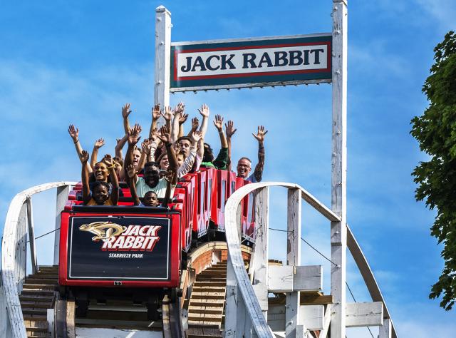 People raise their arms in glee at the first drop on the Jack Rabbit roller coaster at Seabreeze Amusement Park
