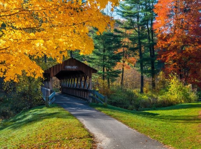 The Thomas L. Kelly Covered Bridge surrounded by fall foliage colors of yellow, green and orange