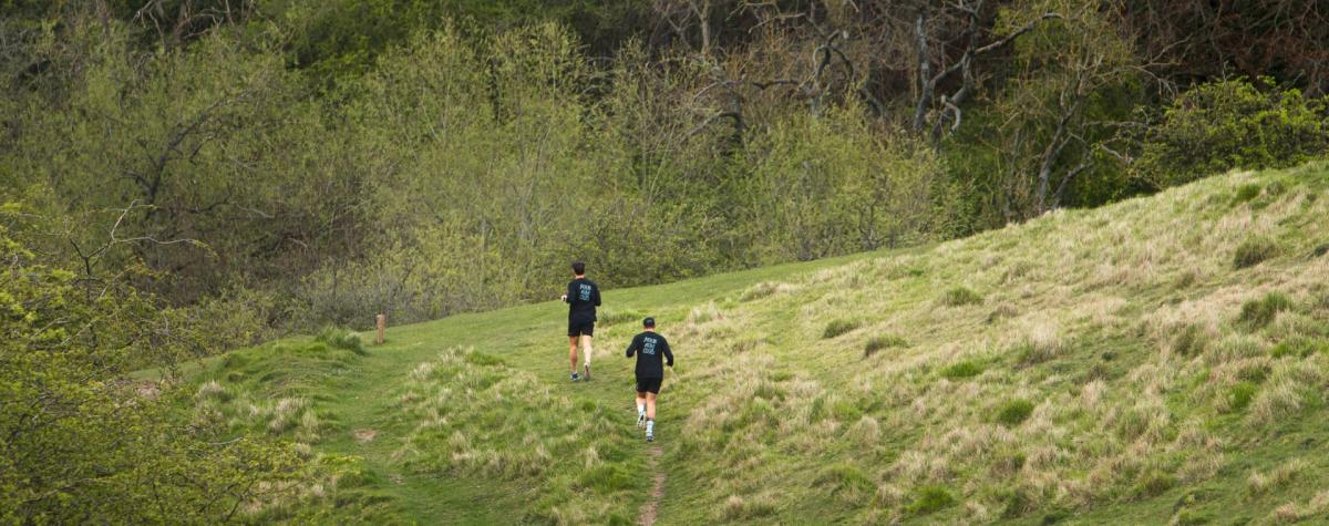 Two members of ALTUS run club running through a field in the Yorkshire Wolds.