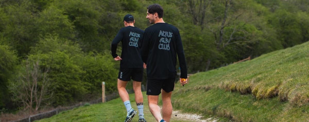 The back of two members of ALTUS running in branded clothing.
