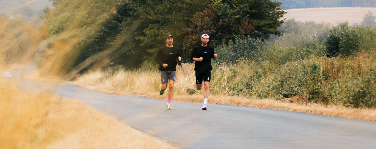 A couple running on a single track path through the Yorkshire Wolds.