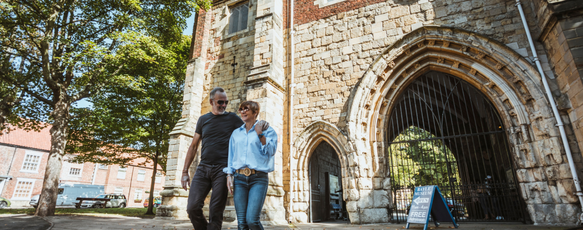 A couple strolling in the sunshine in front of the Bayle Museum in Bridlington's Old Town in East Yorkshire
