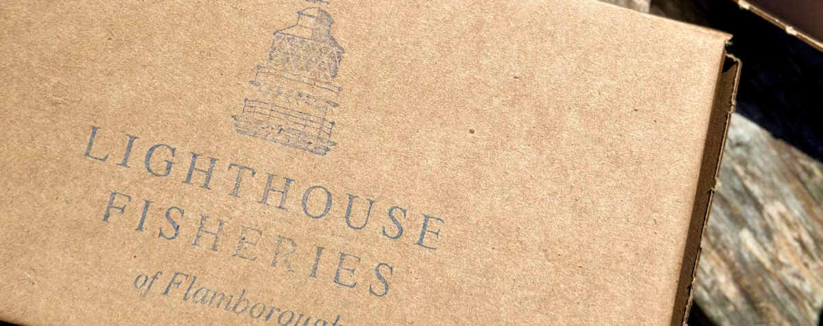 A brown takeaway box with Lighthouse Fisheries of Flamborough printed on the front.