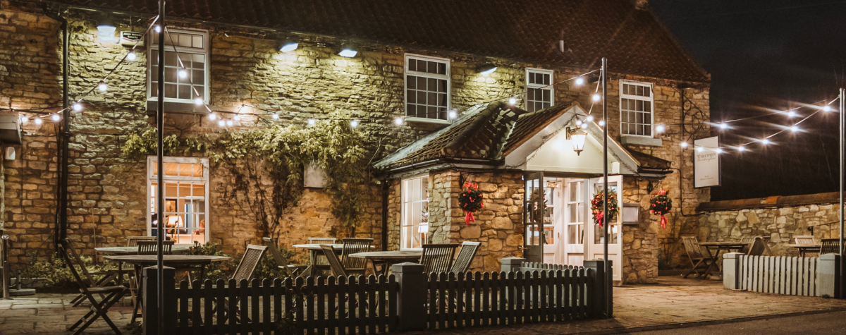 The outside of the Triton Inn in Brantingham at night lit up with cosy lighting