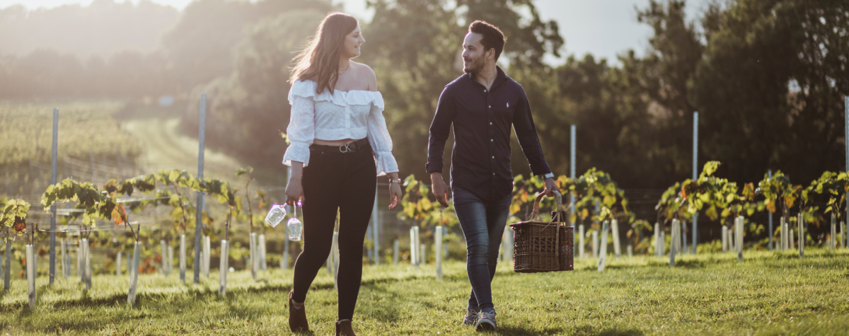 A couple walking with their picnic through the Wolds Vineyard