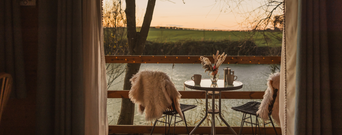 A table and two chairs on some private decking overlooking the lake at sunset at Kingfisher Lakes in East Yorkshire.