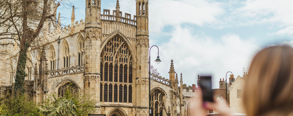 A woman taking a photo on her phone of St Mary's Church, Beverley