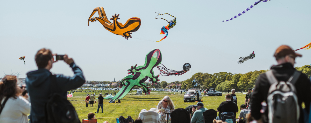 Crowds watching huge colourful kites flying in the sky at the Bridlington Kite Festival in East Yorkshire