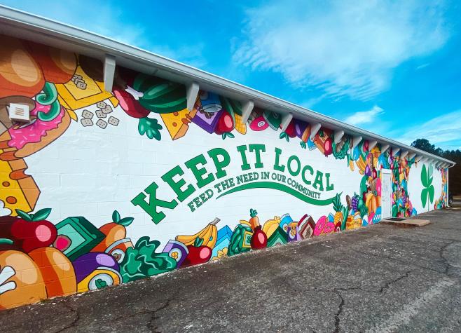 Mural with fresh fruits and vegetables with "keep it local feed the need in our community" written