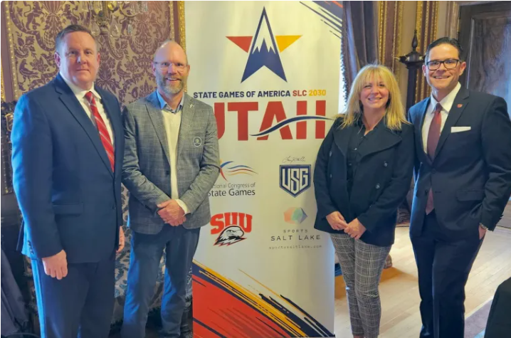 Individuals standing next to a sign announcing the 2030 State Games of America SLC