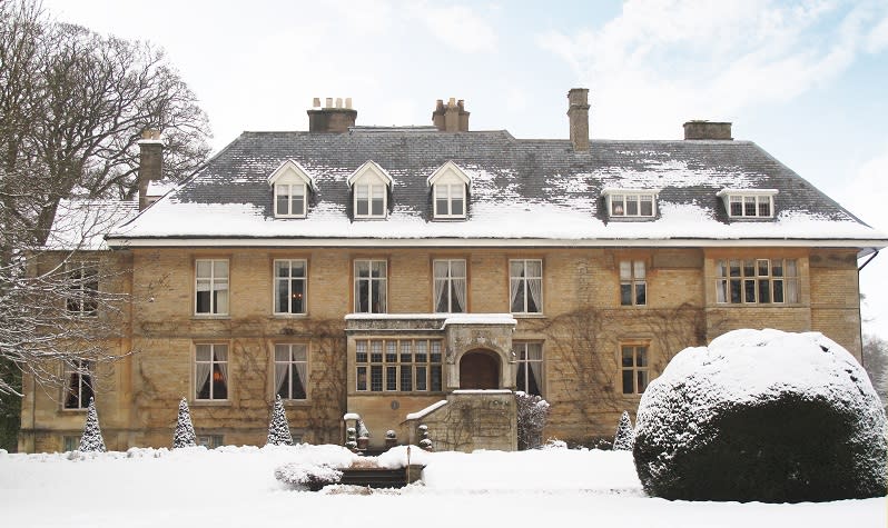 The honey coloured Slaughters Manor House surrounded by snow covered grounds