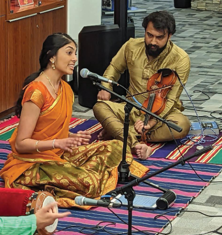 Man and woman sitting on floor singing during Diwali