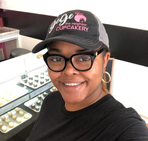 Woman in glasses and hat with gege cupcakery on the hat