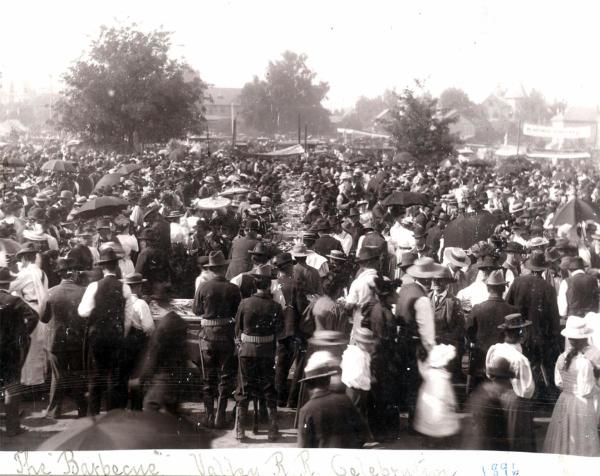 Black and white historical photo showing a crowd gathered around a table at a BBQ for the Valley Railroad Celebration