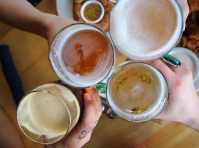 4 patrons holding their beer up in a toast at a brewery in Salt Lake City