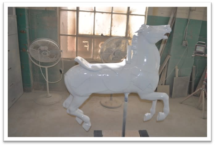 Carousel horse standing up in workshop with new coat of white finish