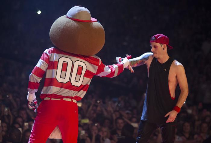 An image of 21 Pilots, Josh Dun shaking hands with Brutus Buckeye on stage