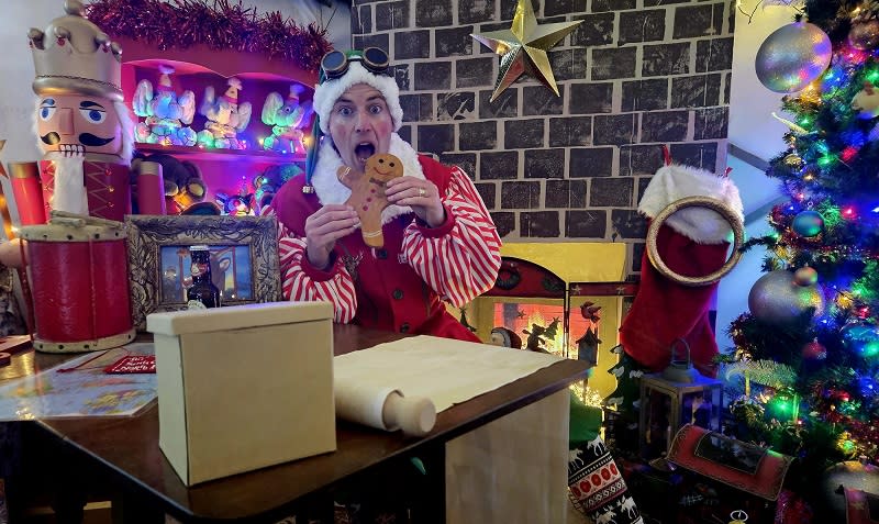 An elf eats a gingerbread man in Santa's toy workshop