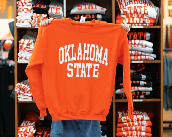 A person holding an Oklahoma State sweatshirt at a clothing store