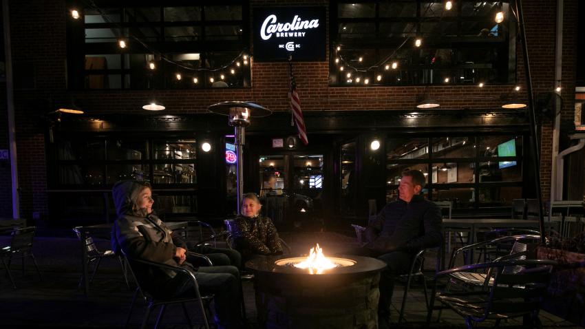 People sitting around a firepit on the outdoor patio at Carolina Brewery