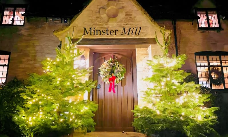 Christmas trees stand either side of the large wooden front door of Minster Mill