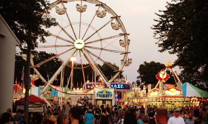 Crowd by food vendors and ferris wheel at the Monroe County Fair