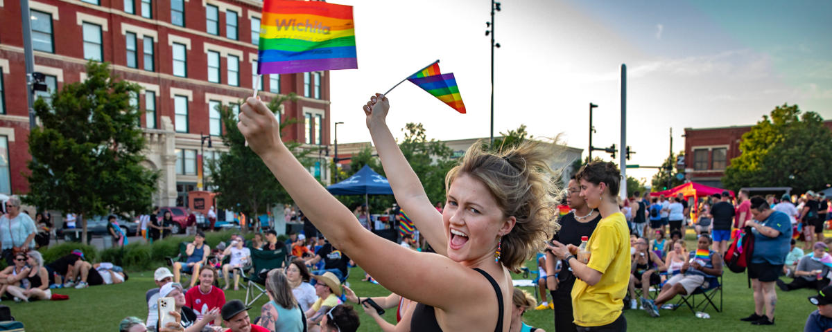 A young woman holds up Pride flags at the Pride Festival in Wichita