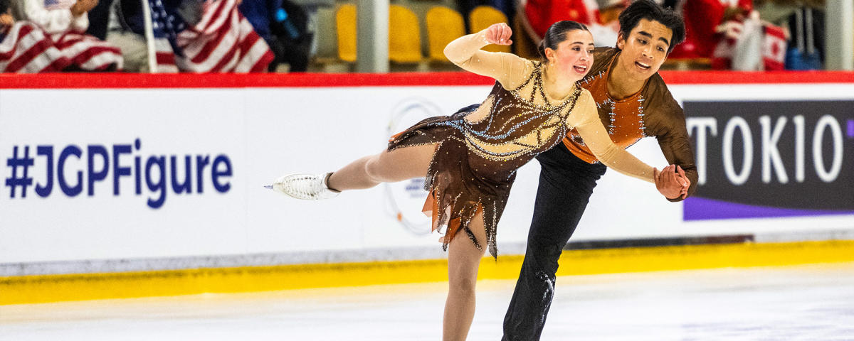 Figure skaters Olivia Flores and Luke Wang glide in unison on the ice during a competition