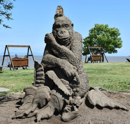 Sand sculpture showing a monkey holding on to some leaves in a park.