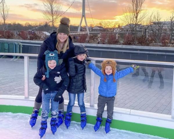 A mom and her three children skating on the rink at Riverside Crossing Park
