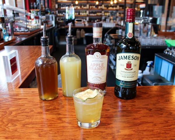 The Dubliner Celtic Cocktail from Market Bar in from of ingredients bottles