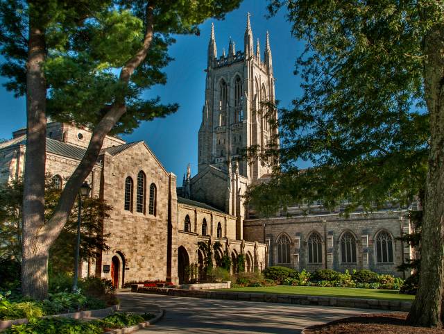Side view of the Bryn Athyn Cathedral, the bell tower is surrounded by green trees.
